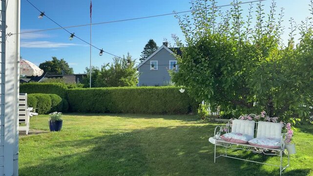 Peaceful backyard garden with green lawn hedges trees and a house on a sunny day