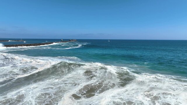 Aerial pan shot of huge waves hitting the coast of the California at Newport beach