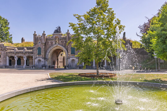 Naarden Vesting, Netherlands. The monumental historic city gate Utrechtse Poort viewed behind a splashing circular water fountain on a sunny summer day.