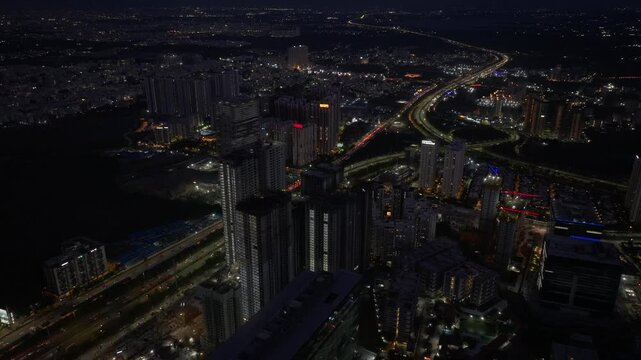 illuminated buildings with outer ring road, traffic flow and Trumpet Interchange at Nanakramguda, kokapet, financial district, hyderabad, telangana, india. night time, static shot, drone shot, 4k.