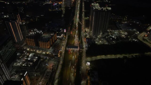 Night View of Jawaharlal Nehru Outer Ring Road exit 19 Toll Plaza with traffic flow and skyscrapers at Nanakramguda, hyderabad, telangana, india. night time, arc shot, drone shot, 4k.