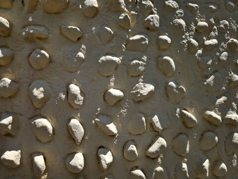 smooth, rounded stones or pebbles embedded in thick, light-colored plaster, mortar, or stucco base. masonry referred to as cobblestone stucco or pebble-dash much chunkier more organized than typical p