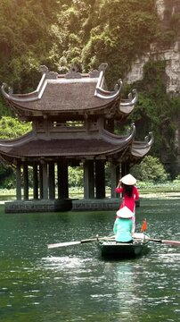 Tourists take a boat trip on the river at Trang An, Ninh Binh Province, Vietnam. Vertical.