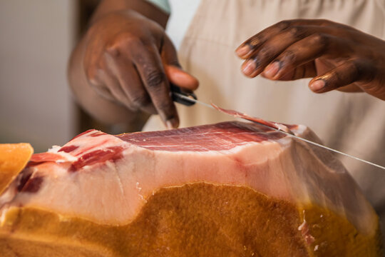 Cortador profesional cortando una fina loncha de jam&oacute;n serrano con un cuchillo jamonero