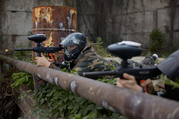 Fototapeta premium A soldier aims a gun while leaning on a pipe, lying on the ground