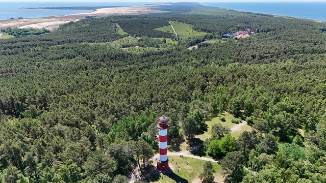 Aerial panoramic view of Nida lighthouse in Curonian Spit national park, Lithuania. Scenic summer landscape with Baltic Sea, lagoon, sand dunes and lush pine forest.