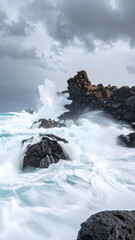 Fototapeta premium Powerful ocean waves crashing against jagged rocks on a dramatic rugged beach.
