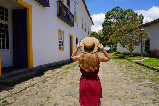 Traveler girl walks through the streets in preserved historic colonial town of Paraty, Rio de Janeiro, Brazil