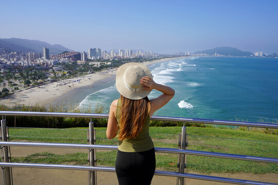 Beautiful young tourist woman enjoying cityscape from belvedere in Guaruja, Sao Paulo, Brazil