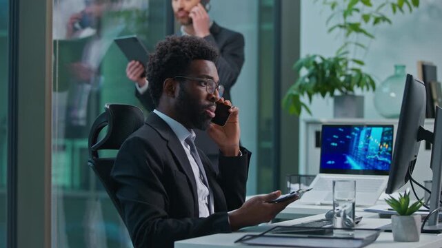 Busy multiethnic coworkers African American Caucasian men talking mobile phone cellphone multitask professional employees businessmen males business office colleagues teamwork consult call cooperate