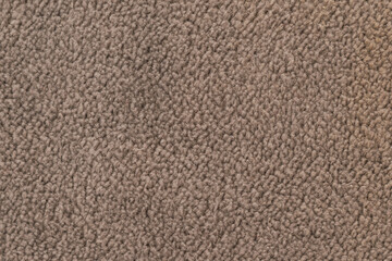 Horizontal close up of a soft brown fleece fabric with dense curly wool fibers on a cozy warm blanket or winter jacket texture surface © moryachka