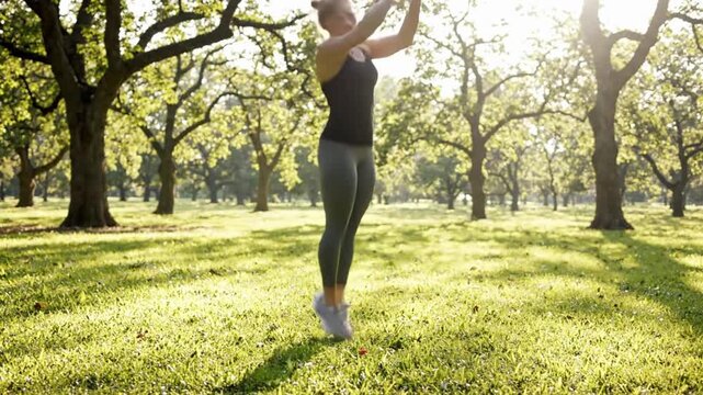 Female athlete performs burpees and press ups in sunny park setting