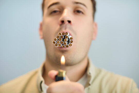 Smoking man with cigarettes shows addiction danger. Close view of a man trying to light many tobacco cigarettes, showing nicotine dependence and health harm. Clear warning about a harmful habit.