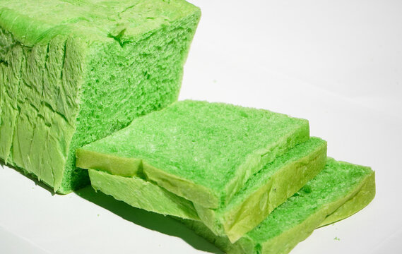 Green pandan bread loaf slice on a white background. Sliced, stale bread with a moldy coating on a wooden plate. Breakfast Concept 