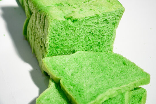 Green pandan bread loaf slice on a white background. Sliced, stale bread with a moldy coating on a wooden plate. Breakfast Concept 