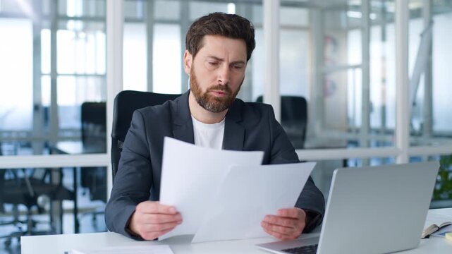 Pensive thoughtful Caucasian middle-aged business man with documents thinking reading letters postal bank notification male mature businessman hold papers read contract job report think in office
