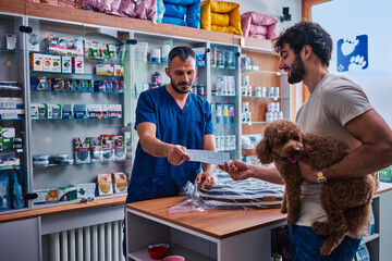 Fototapeta premium Veterinarian giving prescription to pet owner with poodle