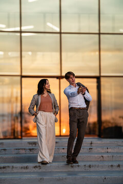 Business professionals communicating on steps at sunset