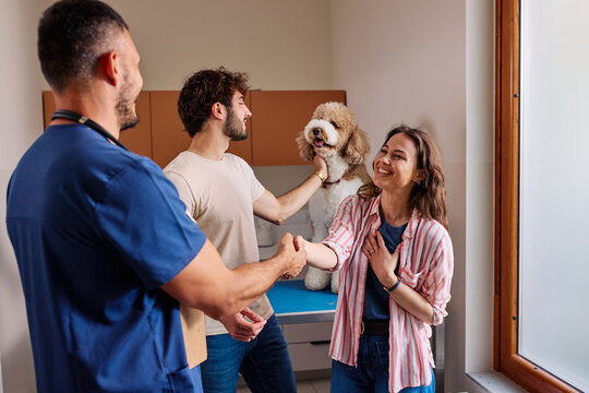 Veterinary doctor shaking hands with happy couple