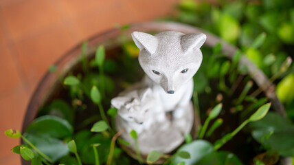 Fototapeta premium Decorative fox statue with greenery in a garden