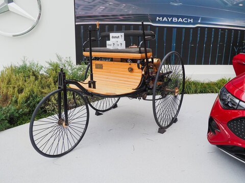 TOKYO, JAPAN - May 6, 2026: Mercedes-Benz Patent-Motorwagen replica with 'I'm donut ?' boxes and a CLA by Mercedes-Benz Studio Tokyo, which includes a caf&eacute; by 'I'm donut ?'. A Maybach is on a screen.