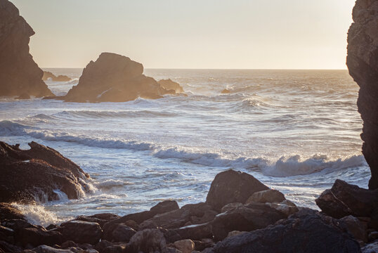 Praia da Ursa, Portugal: Waves breaking on a rocky coast at sunset