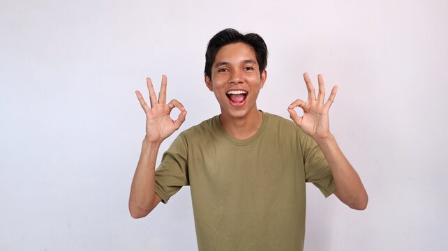 Excited young Asian man gesturing okay with hand. copy space, success, happiness, say yes, okay, good, delicious