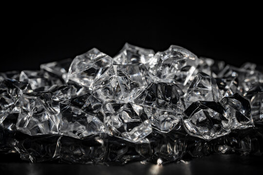 Closeup of artificial acrylic ice cubes with glowing highlights on dark glossy surface for cold beverage and luxury product commercial advertising