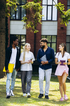 Diverse group of college students walking and communicating outdoors on a university campus, representing friendship and education
