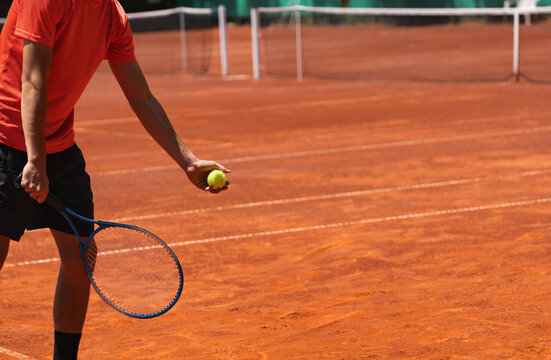 Minimal clay tennis court scene with male young player preparing to serve and wide background copy space for sports advertising, banners and promotional design