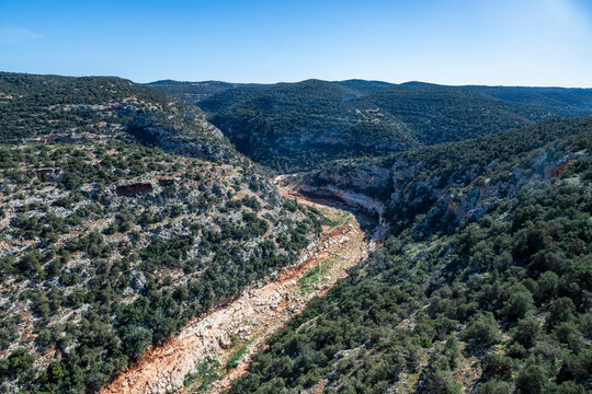 Vast view of Wadi al Kuf gorge with rocky hills and greenery in Libya under clear sky