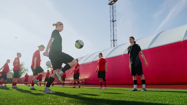 Womens soccer team practicing ball control and passing drills on outdoor training field under clear sky, focusing on coordination, fitness, and teamwork development