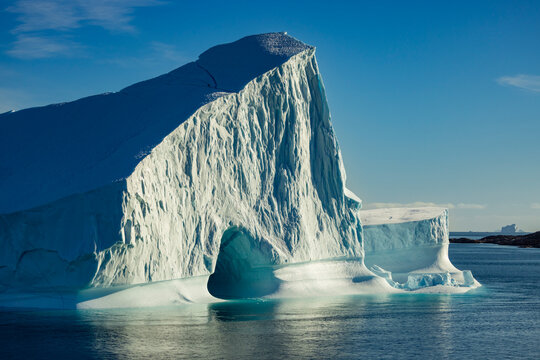 Monolithic iceberg towers above cold waters in morning light near Bjorneoer in Greenland