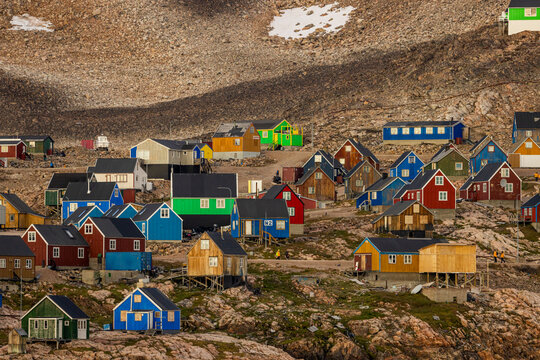 Colorful homes stand out on tundra slopes in a remote Greenland settlement surrounded by rugged terrain