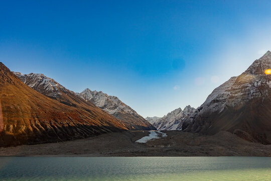Glacier winds through valley walls and meets green water in remote Blomsterbugten, Greenland