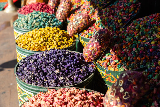 Colorful spices and souvenirs for sale at a market in Marrakesh, Morocco during a busy day