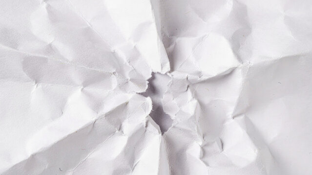Crushed paper with a tear close up macro photography on a white background crumpled wrinkled
