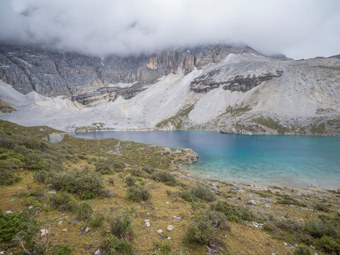 Visit to the shoreline of Five-Color Lake with turquoise water and grey mountain slopes in Yading Nature Reserve, Daocheng, Sichuan, China