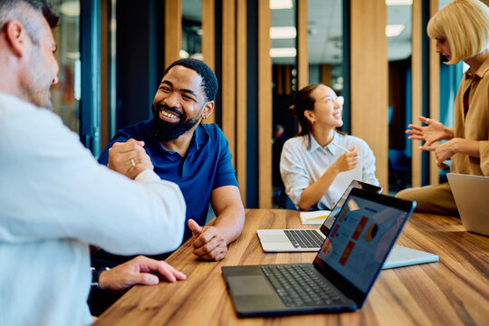 Diverse business professionals celebrating partnership with a handshake and smiles, collaborating during a meeting in a modern office