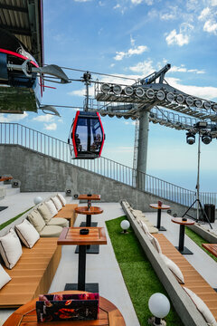 Cable car station with an open-air cafe-lounge and a view of a passing cabin.