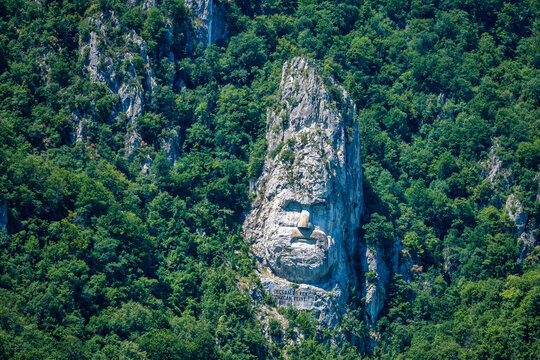 Decebalus rock sculpture stands tall over the Danube river in Romania's Orsova region in summer sunlight reflecting history and culture