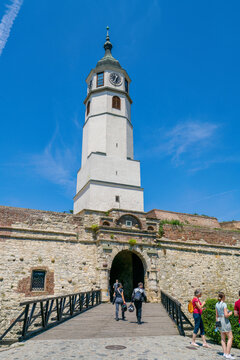 Visitors enter Sahat Kula clock tower at Belgrade Fortress during daytime in Serbia with clear skies and historical architecture