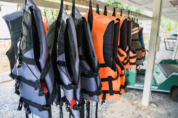 Obraz premium Row of Life Jackets: A colorful assortment of life jackets hangs neatly on a rack, ready for adventure, suggesting water activities and safety.