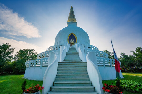 White Peace Stupa dome with golden spire under sunny sky in Zalaszanto, Hungary