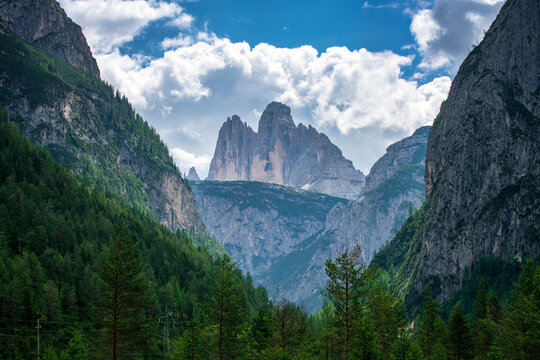 Majestic mountain peaks rise above green valleys and trees in Dolomites, Italy in daylight hours