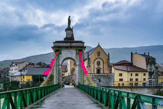 Seyssel village on Rhone river with historic bridge and church under cloudy sky in France