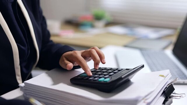 Businesswoman calculating financial data on a calculator in a modern office