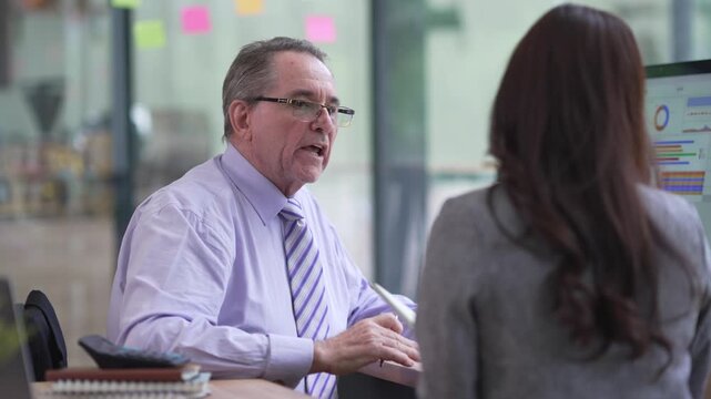 Senior business manager instructing a female colleague during an office meeting