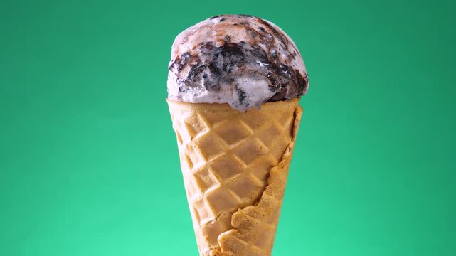 Ice cream in a waffle cone slowly rotates against a bright colored background