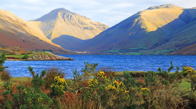 View of mountains and lake from a distance in the Lake District showing a bright day with blue sky in Cumbria, England